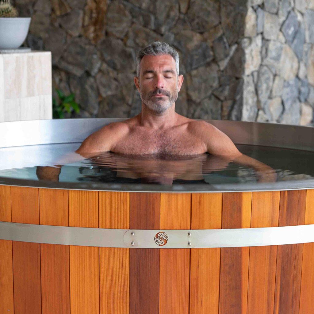 A man enjoying a relaxing soak in a wooden hot tub, representing spa services.