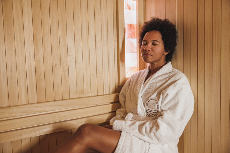 A woman relaxing in a sauna, enjoying the benefits of heat therapy.