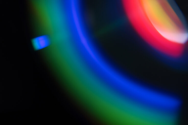 Abstract image featuring vibrant blue light along with other colors on a dark background.