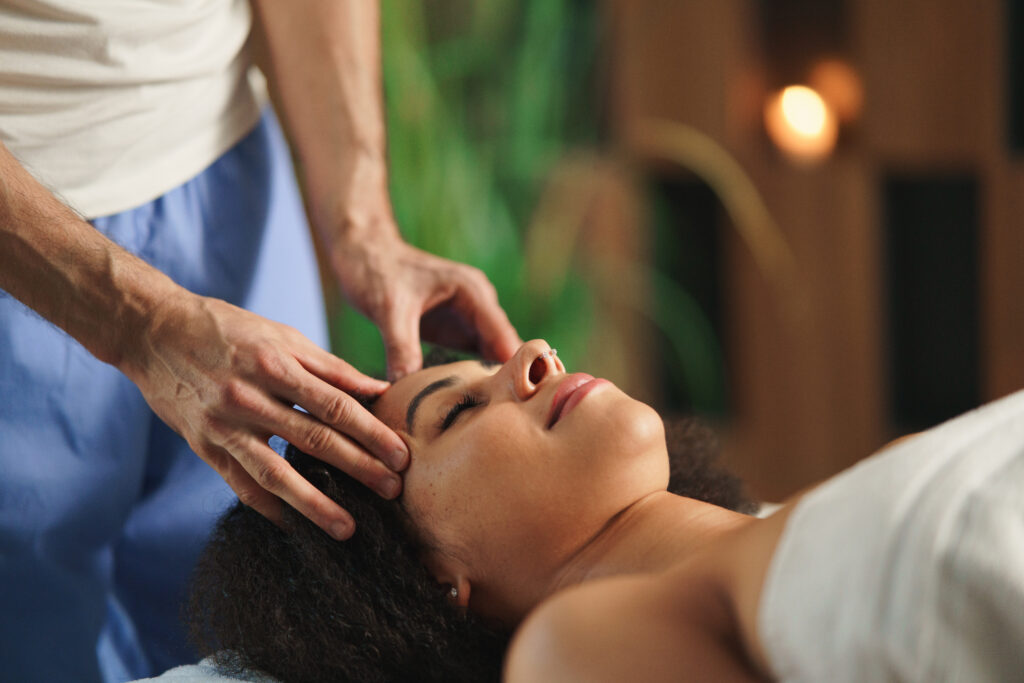 Young woman enjoying a relaxing head massage at a spa, illustrating the healing touch and whole-body wellness benefits.
