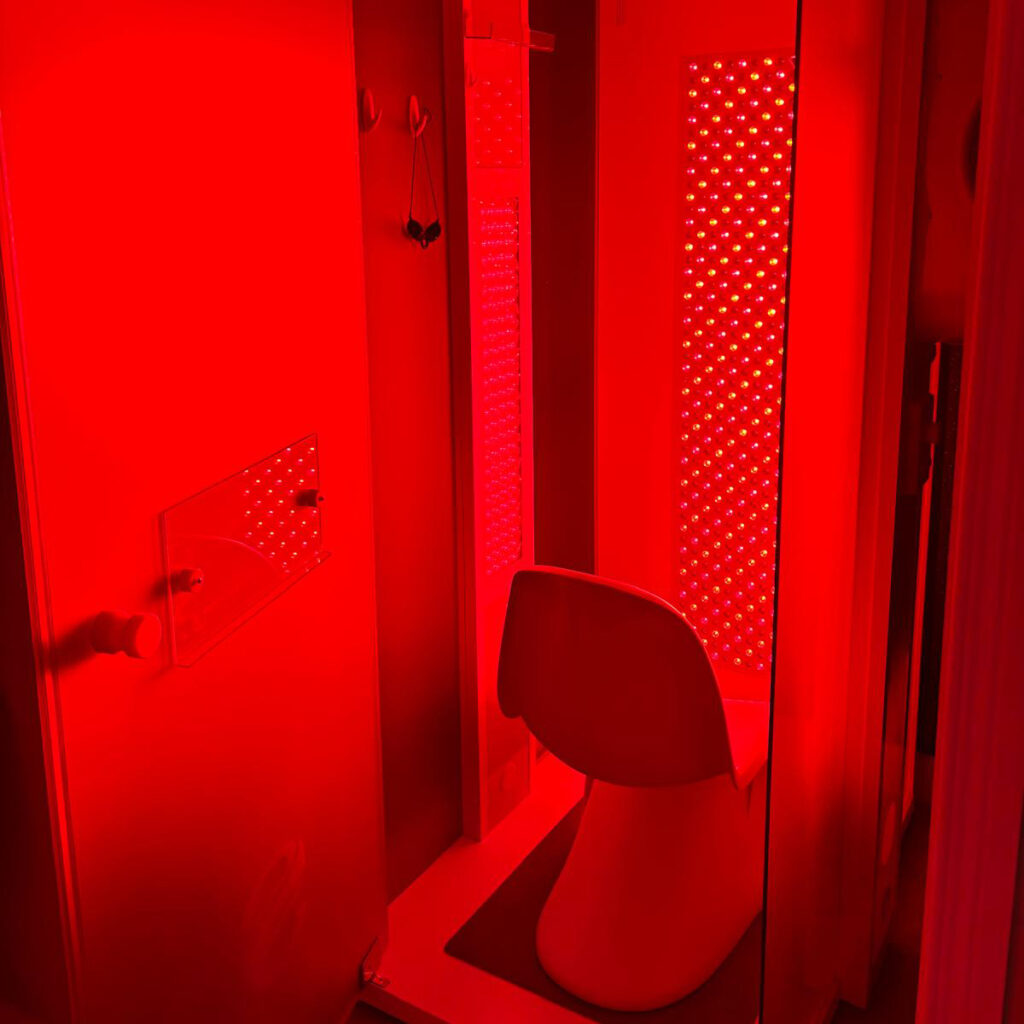 Red light therapy booth glowing inside a wellness center