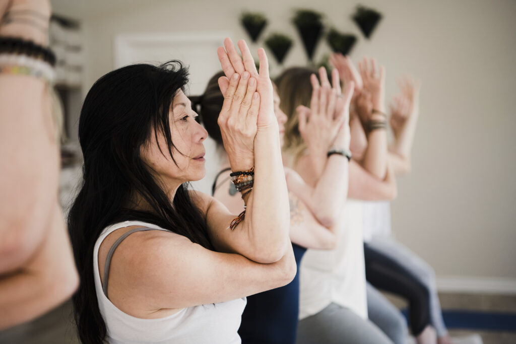 Women in a grounding yoga pose with eagle arms during a group class at The Yoga Spa