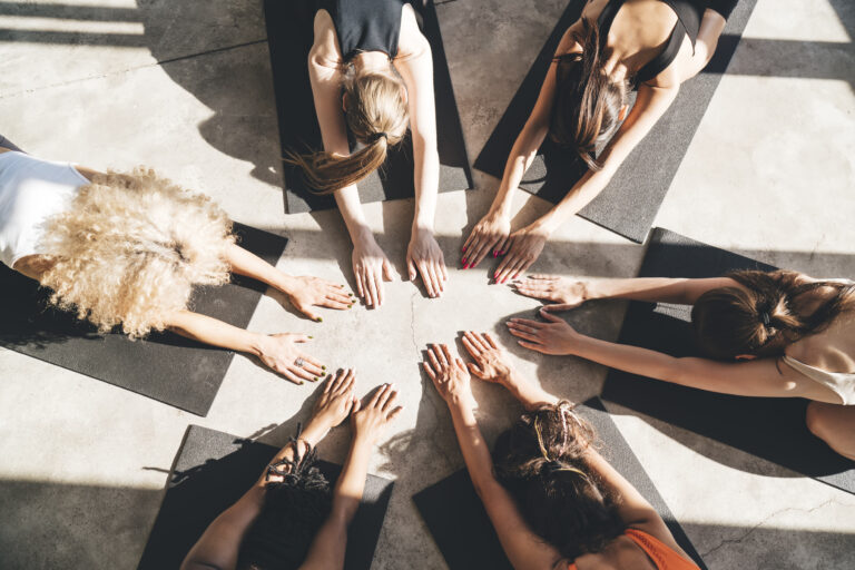 Group of women practicing inner compass yoga in a circle, embodying intuitive goal setting and mind-body alignment